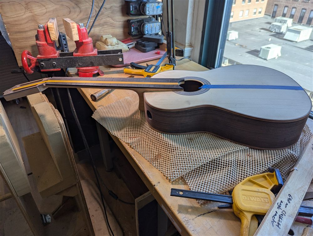Neck and fretboard binding work on the classical guitar, clamped in a vise.