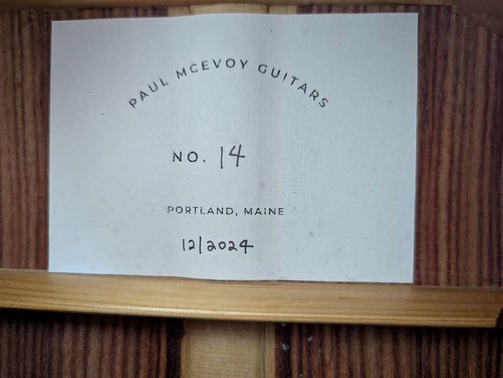 Interior shop label reading Paul McEvoy Guitars No. 14, Portland, Maine, visible through the soundhole.